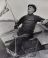 Hendrik Voordewind is, zeilende in zijn aakje ‘Dolphijn’, duidelijk niet met één ding tegelijk bezig. (Foto: uit H. Voordewind: Voor de Wind, 1951)